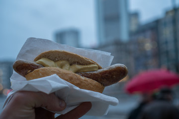 man holding street food with long frankfurter sausage