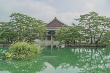 Obraz premium One of the palaces surrounded by water, with a reflection of the rooftop and trees, in Gyeongbokgung Palace, Seoul, South Korea