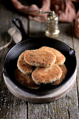 Fish cutlets in breadcrumbs in a cast-iron frying pan.