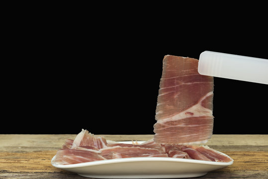 plato con jam&oacute;n , loncha de jam&oacute;n  sujeta con una pinza
