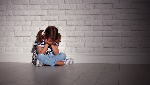 Upset Sad Sad Child Girl In Stress Cries At An Empty Dark Wall