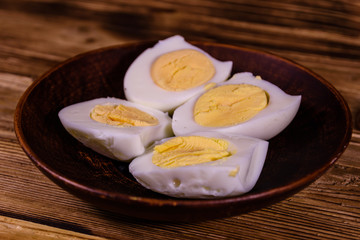 Ceramic plate with peeled boiled eggs on wooden table