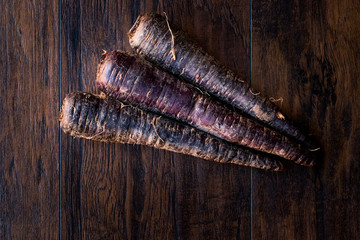 Purple Carrots on Dark Wooden Surface.