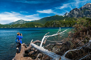 Hiker taking pictures of the mountains on the lake coast