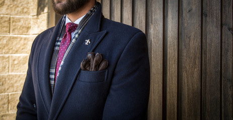 Serious successful man in elegant expensive tailored suit standing in front of wooden door