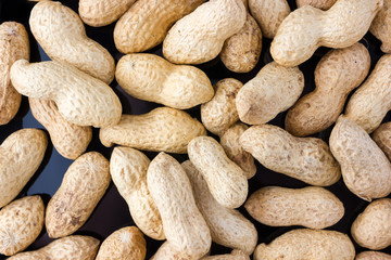 Fried peanuts in shell. Peanut in shell on a black background close-up.
