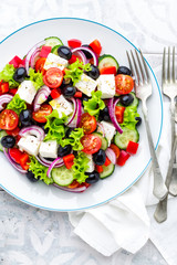 Greek salad of fresh cucumber, tomato, sweet pepper, lettuce, red onion, feta cheese and olives with olive oil. Healthy vegetarian food