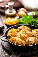 Cabbage rolls stewed with meat and vegetables in pan on dark wooden background