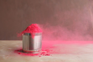 Bright colors for holi festival. Pink holi paint in a cup with bleaching powder on a table. Close...