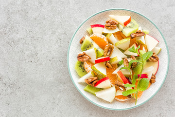 Fruit salad of fresh sweet apple, pear, tangerine and walnuts. Healthy vegetarian food