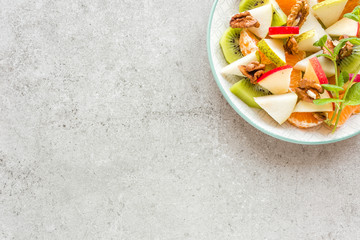 Fruit salad of fresh sweet apple, pear, tangerine and walnuts. Healthy vegetarian food