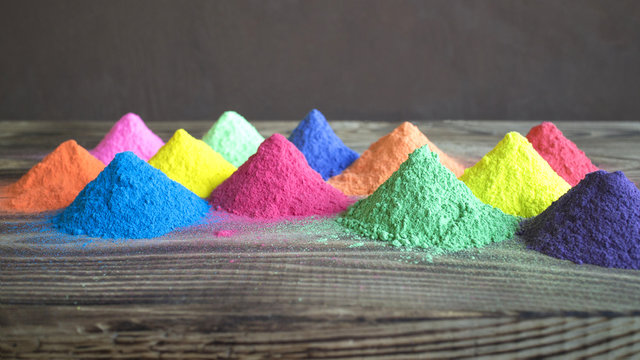 Bright colors for holi festival. Colorful holi paint in the form of pyramids on a wooden brown table  with copy space. Natural organic pigment.