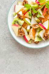 Fruit salad of fresh sweet apple, pear, tangerine and walnuts. Healthy vegetarian food
