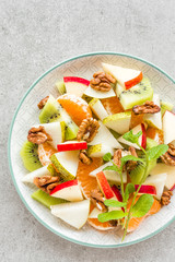 Fruit salad of fresh sweet apple, pear, tangerine and walnuts. Healthy vegetarian food