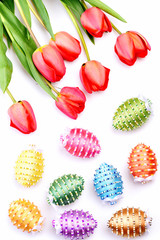 Bunch of flowers near decorated Easter eggs in different colors.