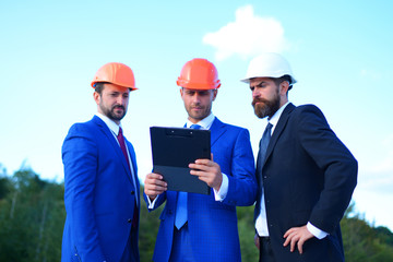 Board of architects with confident faces in suits and helmets