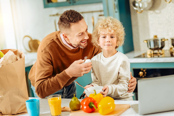 Caring father. Happy nice positive man smiling and looking at his son while caring about him