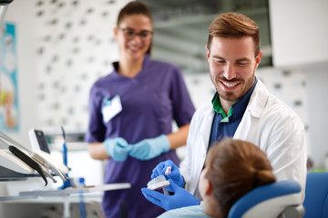 Fototapeta premium Dentist shows properly brushing teeth to patient on model of teeth in jaw