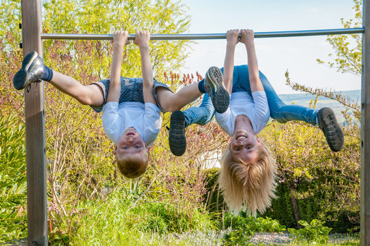 zwei gesunde Kinder turnen drau&szlig;en und trainieren ihre Muskeln und Balance