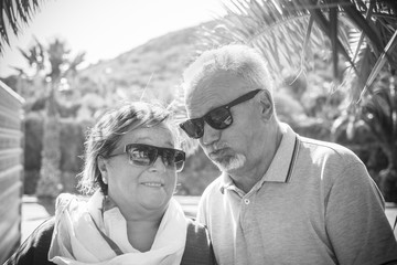 Elderly couple with white hair and sunglasses play and grimaces outdoors in the summer