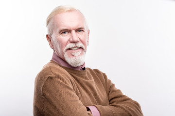 Obraz premium Forever young. The portrait of a charming senior man with a white beard and an earring in his ear standing half-turned and posing isolated on a white background
