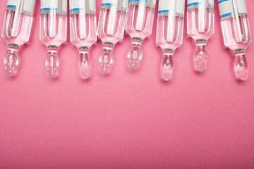 Cosmetic preparations in ampoules on a pink background. Copy space.