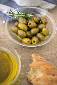 Green olives in the bowl with fresh rosemary served for snack.