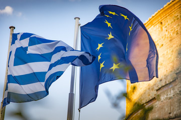Greek flag and European Flag blowing and waving in the wind one next to another