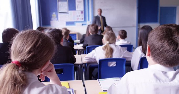 4k, Group of school kids sitting and listening to teacher in classroom from back