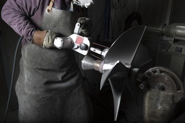 Heavy industry worker whit grinder boat propeller