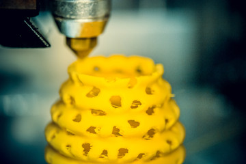 3d printer printing objects yellow form closeup. Modern technical 3D printing.