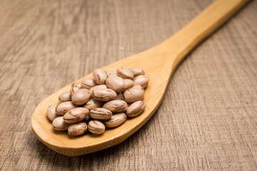 Pinto Bean legume. Spoon and grains over wooden table.