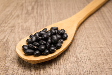 Black Turtle Bean legume. Spoon and grains over wooden table.