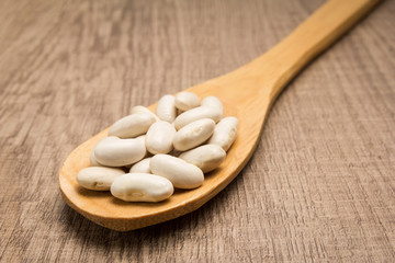 Navy Bean legume. Spoon and grains over wooden table.