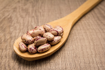 Sugar Bean legume. Spoon and grains over wooden table.