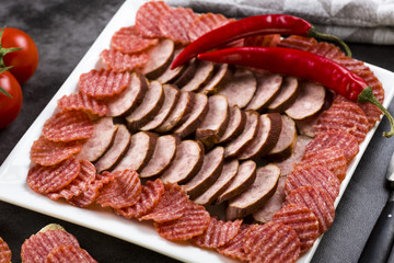 a plate of sliced cold meats - delicious smoked sausage and spicy salami - a photo in a rustic style.