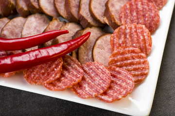 a plate of sliced cold meats - delicious smoked sausage and spicy salami - a photo in a rustic style.