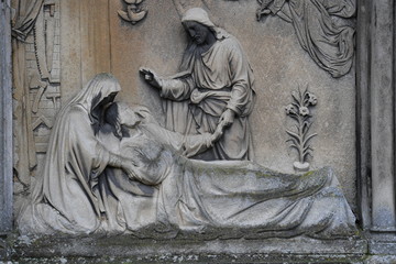 Tombstone sculpture of Jesus Christ who is healing a sick man