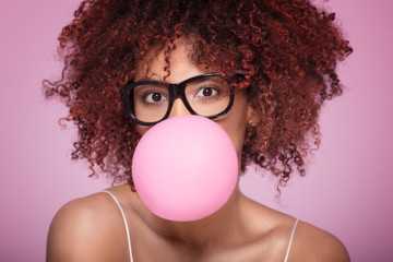 Afro girl blowing bubble gum balloon.
