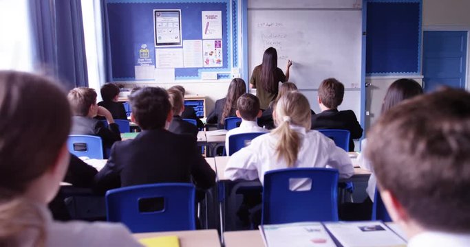4k, Group of school kids sitting and listening to teacher in classroom from back