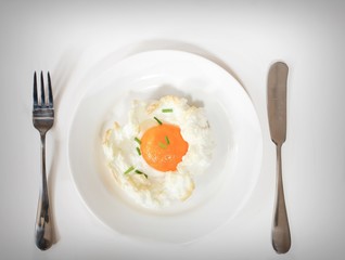Baked cloud Egg in a white plate with fork and spoon on side