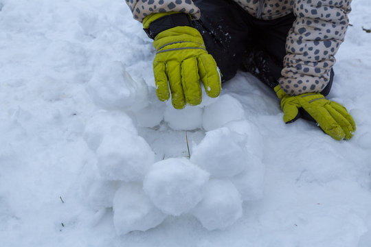 Ett barn bygger en sn&ouml;lykta en vinterdag