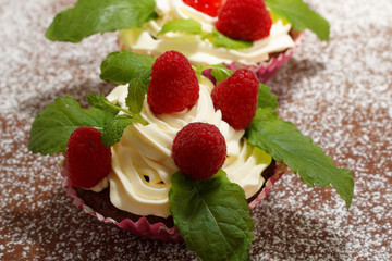 Homemade delicious chocolate cupcakes with fresh raspberry and cream on top. Delicious cupcake for Valentine’s Day. 
