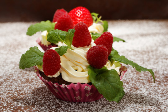 Homemade delicious chocolate cupcakes with fresh raspberry and cream on top. Delicious cupcake for Valentine’s Day. 
