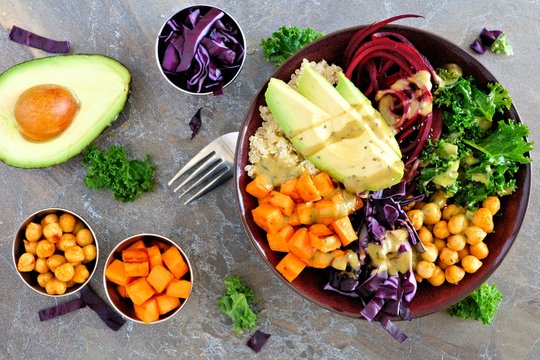Buddha bowl with quinoa, avocado, chickpeas, vegetables on a dark stone background, Healthy eating concept. Overhead scene.
