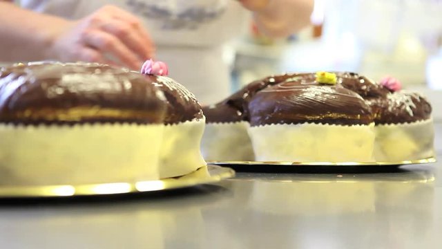 pastry chef hands garnish Easter sweet bread cakes with flowers fondants sugar paste, closeup on the worktop in confectionery