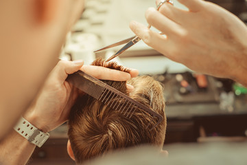 Barbershop. Close-up of man haircut, master does the hair styling in barber shop. Toned vintage...