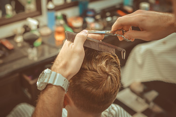 Barbershop. Close-up of man haircut, master does the hair styling in barber shop. Toned vintage...