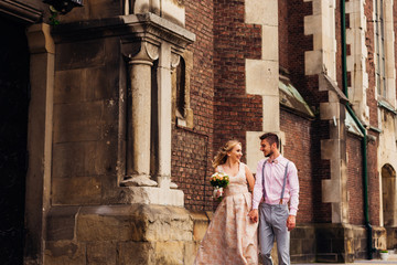 girl in a long dress holds a bouquet and her boyfriend next to her and they walk together around a...