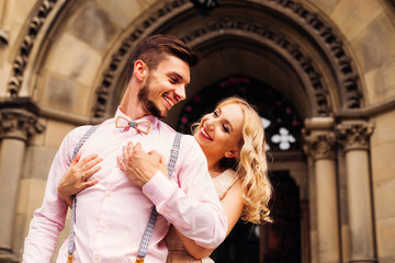 Close-up of a girl who gently hugs her boyfriend and laughs at him near a beautiful arc with columns